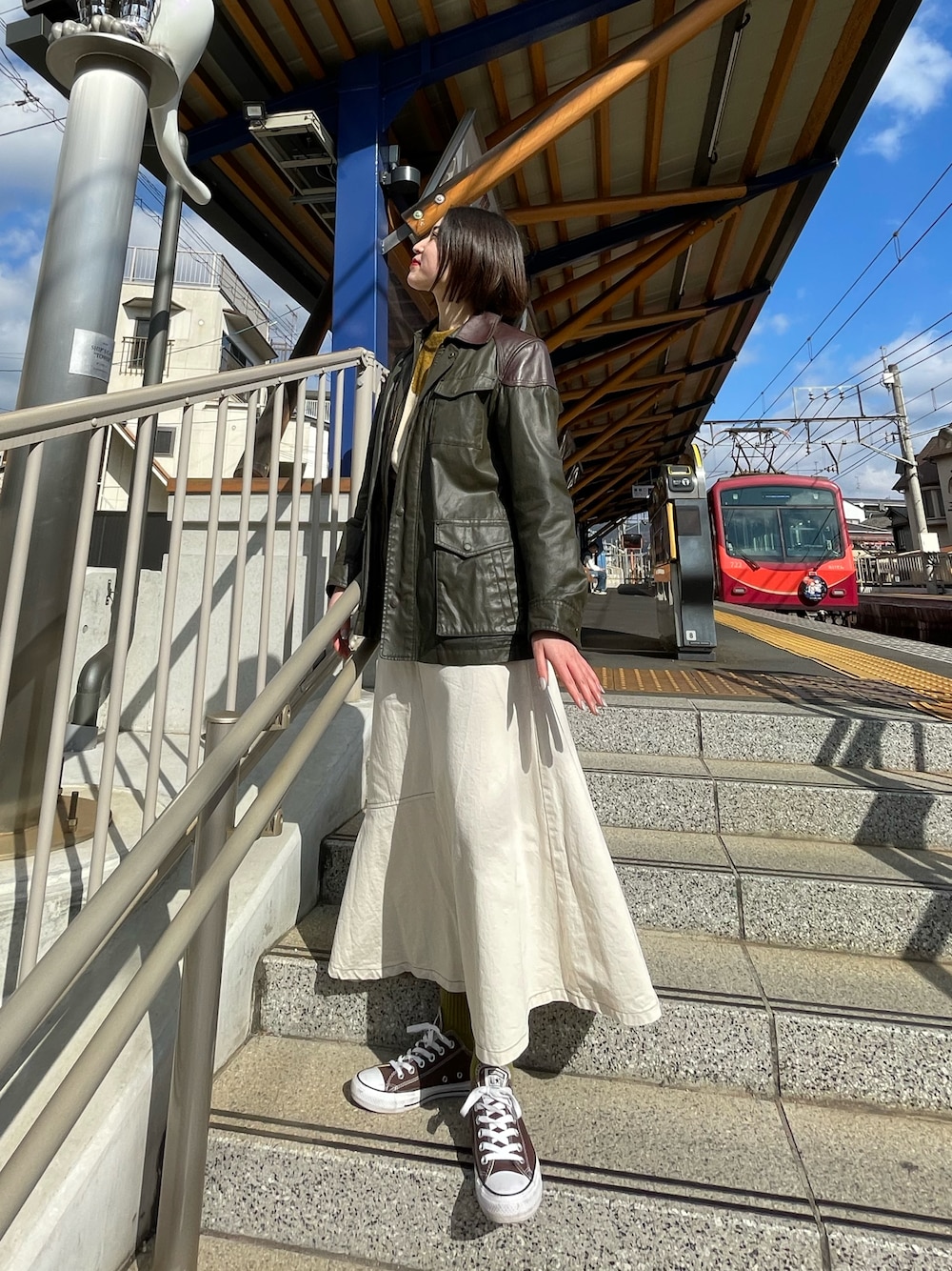 ブラウン系のスニーカー、ホワイト系のスカートを着用したレディースの秋コーディネートの1枚目の写真