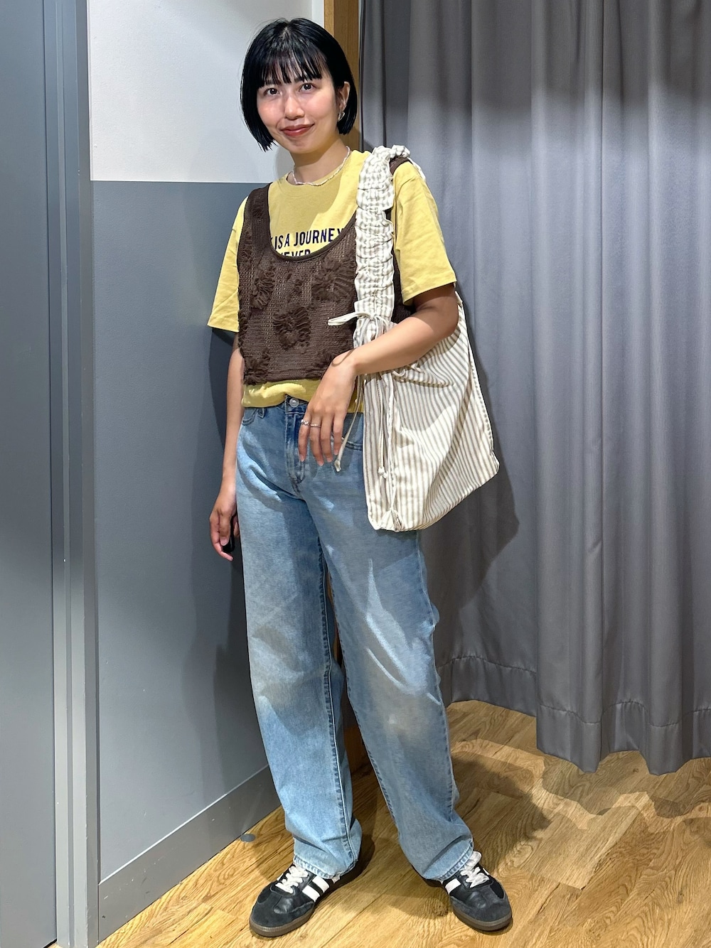 ブラウン系のベスト、ブルー系のデニムパンツ、ベージュ系のトートバッグを着用したレディースの夏コーディネートの1枚目の写真