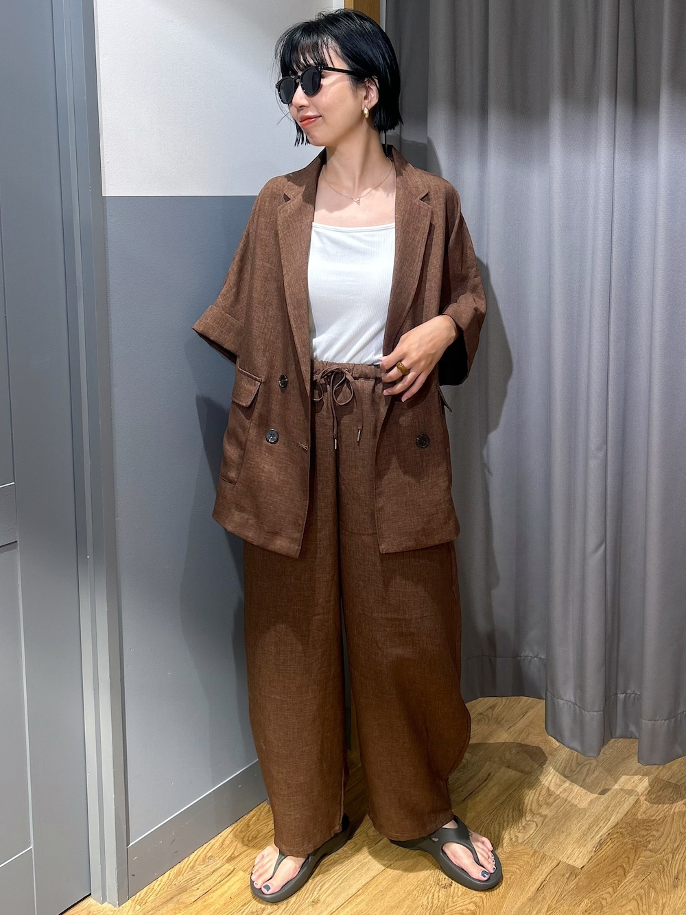 ブラウン系のテーラードジャケット、ブラウン系のその他パンツ、ホワイト系のタンクトップを着用したレディースの夏コーディネートの1枚目の写真