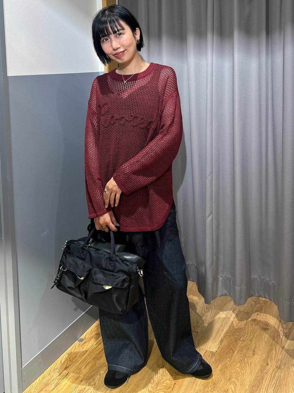 レッド系のニット/セーター、ブラック系のタンクトップ、ブルー系のデニムパンツを着用したレディースの秋コーディネートの1枚目の写真
