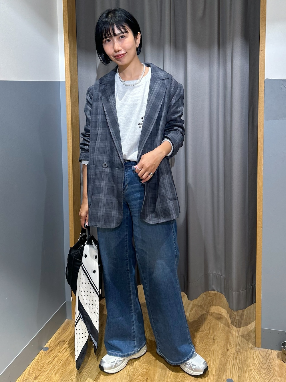 グレー系のテーラードジャケット、グレー系のTシャツ/カットソー、ブルー系のデニムパンツを着用したレディースの秋コーディネートの1枚目の写真