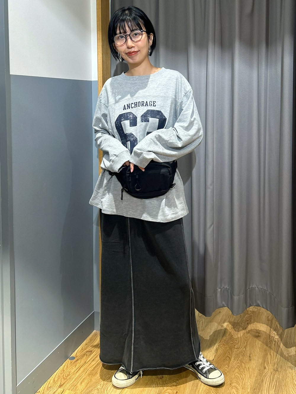 グレー系のTシャツ/カットソー、グレー系のスカート、ブラック系のボディバッグ/ウエストポーチを着用したレディースの秋コーディネートの1枚目の写真