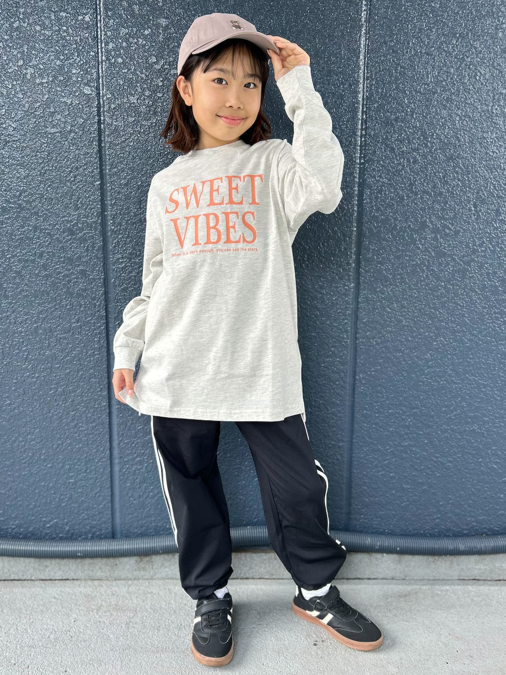 ブラック系のその他パンツ、ホワイト系のTシャツ/カットソー、ベージュ系のキャップを着用したキッズの秋コーディネートの1枚目の写真