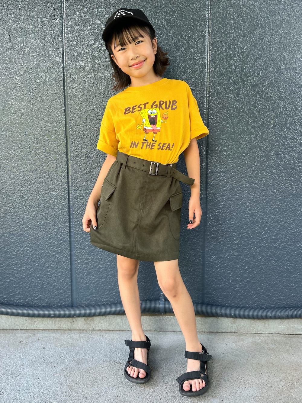 イエロー系のニット/セーター、ブラウン系のその他パンツ、ブラック系のキャップを着用したキッズの夏コーディネートの1枚目の写真