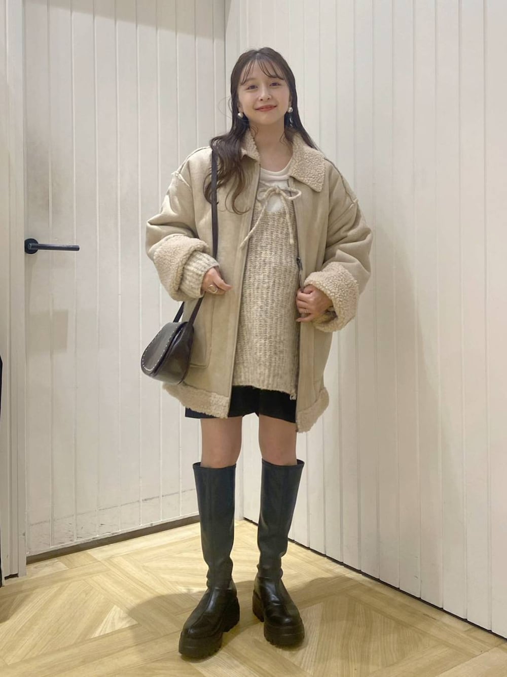 ベージュ系のブルゾン、ブラウン系のショルダーバッグ、ホワイト系のニット/セーターを着用したレディースの秋コーディネートの1枚目の写真