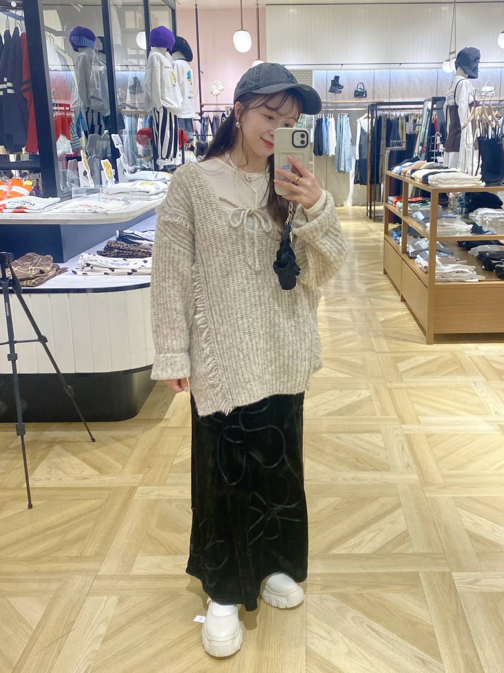ホワイト系のニット/セーター、ホワイト系のスニーカー、ブラック系のスカートを着用したレディースの秋コーディネートの1枚目の写真