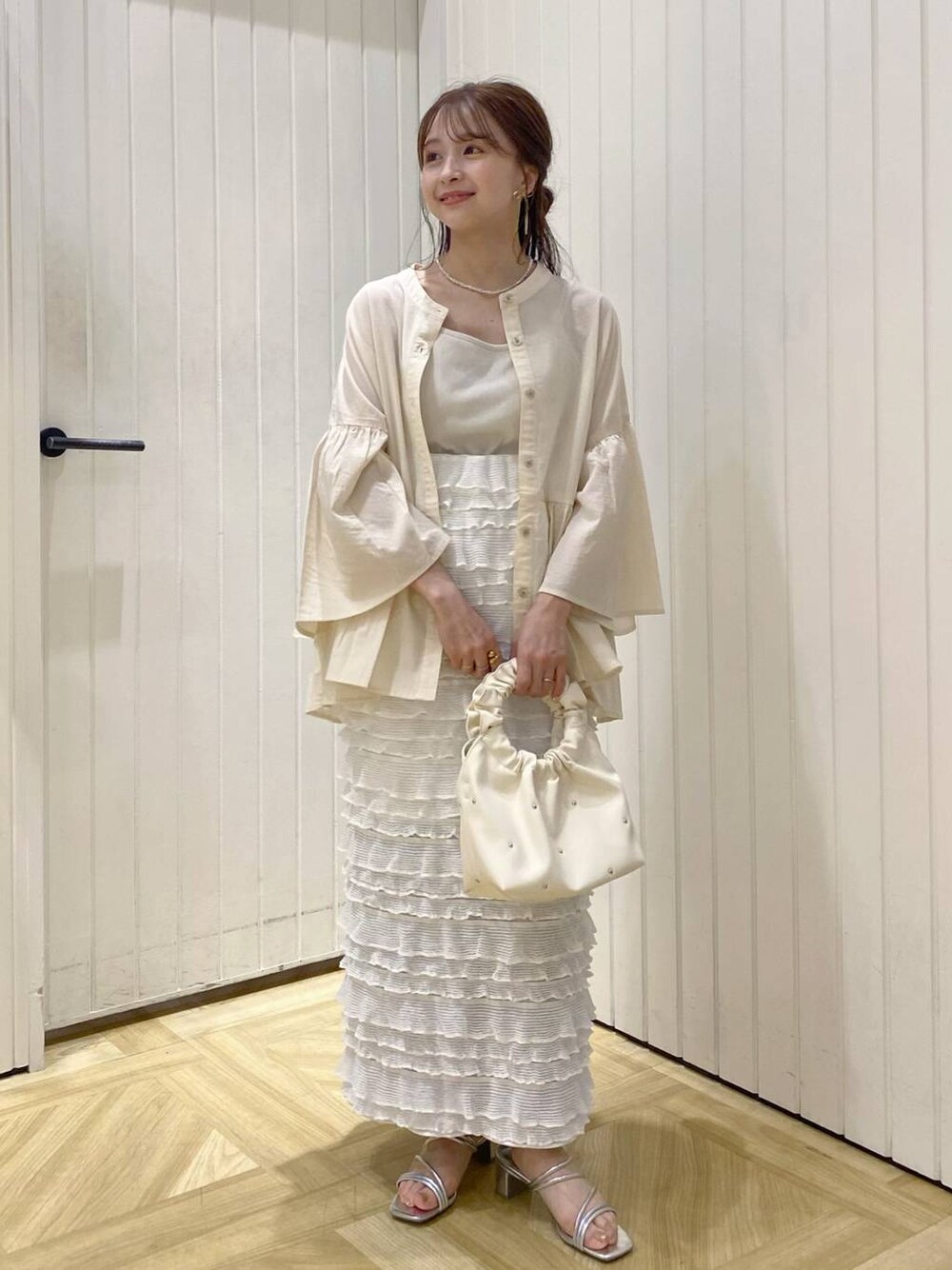 ホワイト系のスカート、ベージュ系のハンドバッグ、ホワイト系のシャツ/ブラウスを着用したレディースの春コーディネートの1枚目の写真