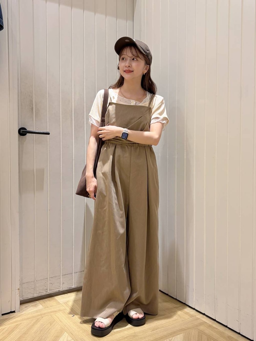 ブラウン系のショルダーバッグ、ホワイト系のサンダル、ホワイト系のTシャツ/カットソーを着用したレディースの春コーディネートの1枚目の写真