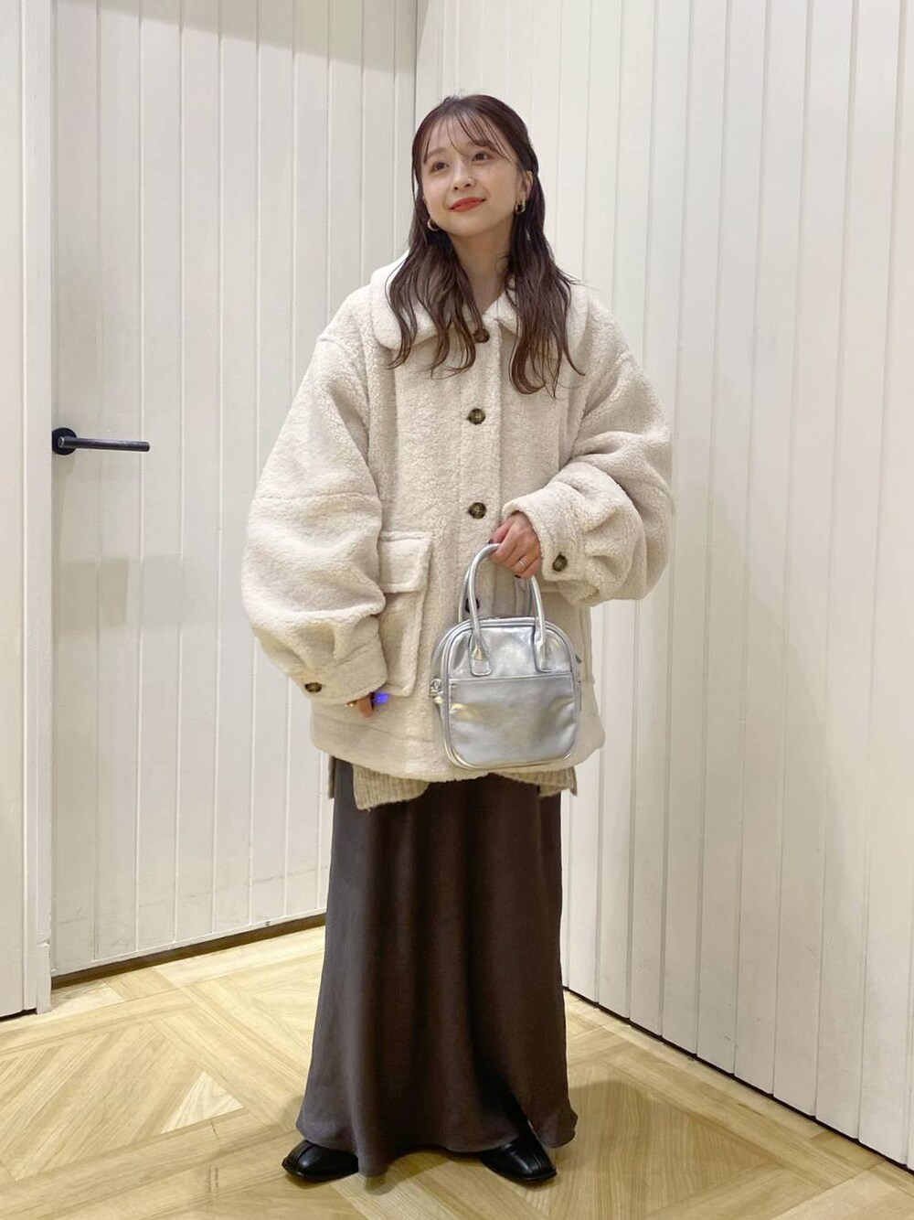 ホワイト系のブルゾン、ブラック系のパンプス、グレー系のスカートを着用したレディースの冬コーディネートの1枚目の写真