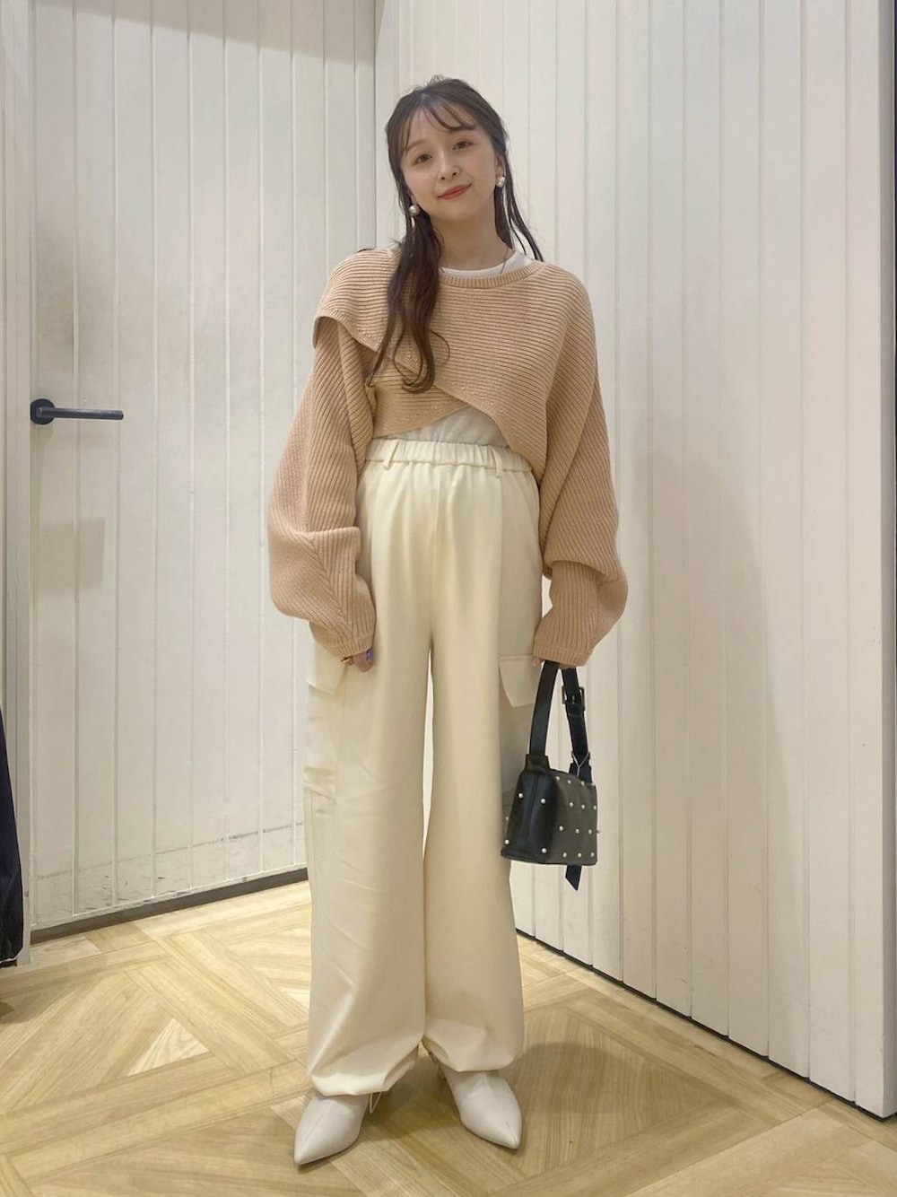 ピンク系のニット/セーター、ホワイト系のスラックス、ホワイト系のブーツを着用したレディースの秋コーディネートの1枚目の写真
