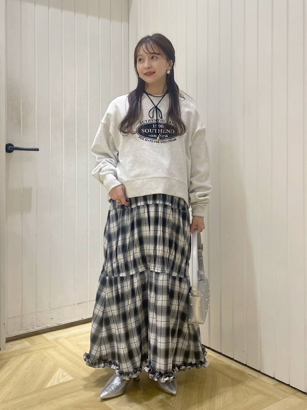 ブラック系のスカート、シルバー系のブーツ、グレー系のスウェットを着用したレディースの秋コーディネートの1枚目の写真