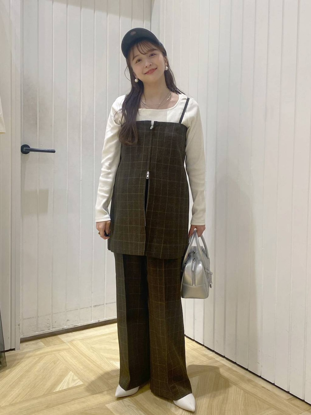 ブラウン系のスラックス、ブラウン系のベスト、シルバー系のボストンバッグを着用したレディースの秋コーディネートの1枚目の写真