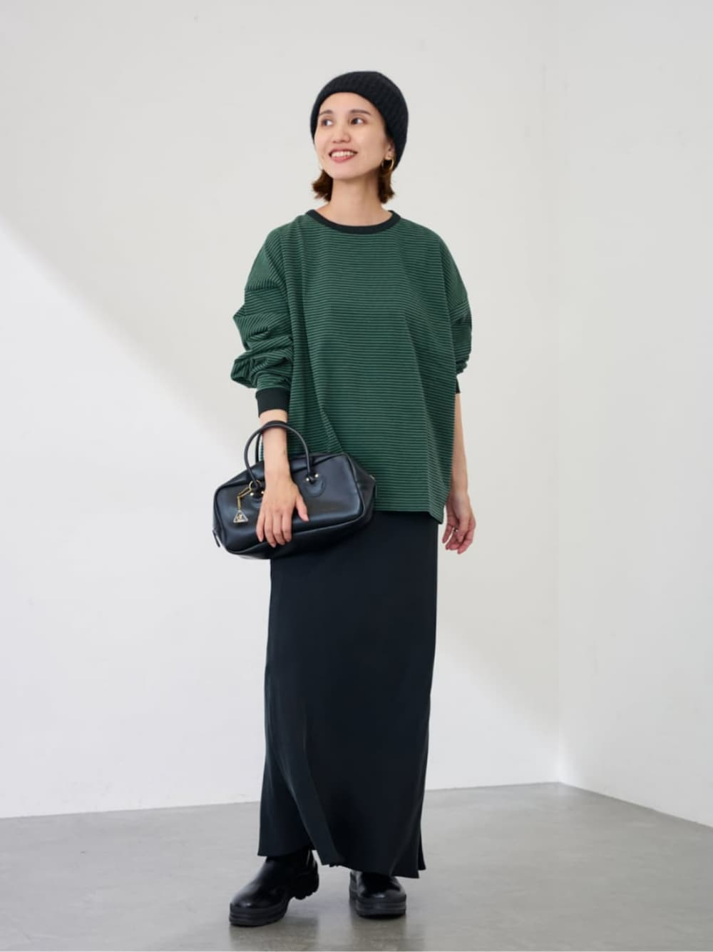 グリーン系のTシャツ/カットソー、ブラック系のスカート、グレー系のニットキャップ/ビーニーを着用したレディースの秋コーディネートの1枚目の写真