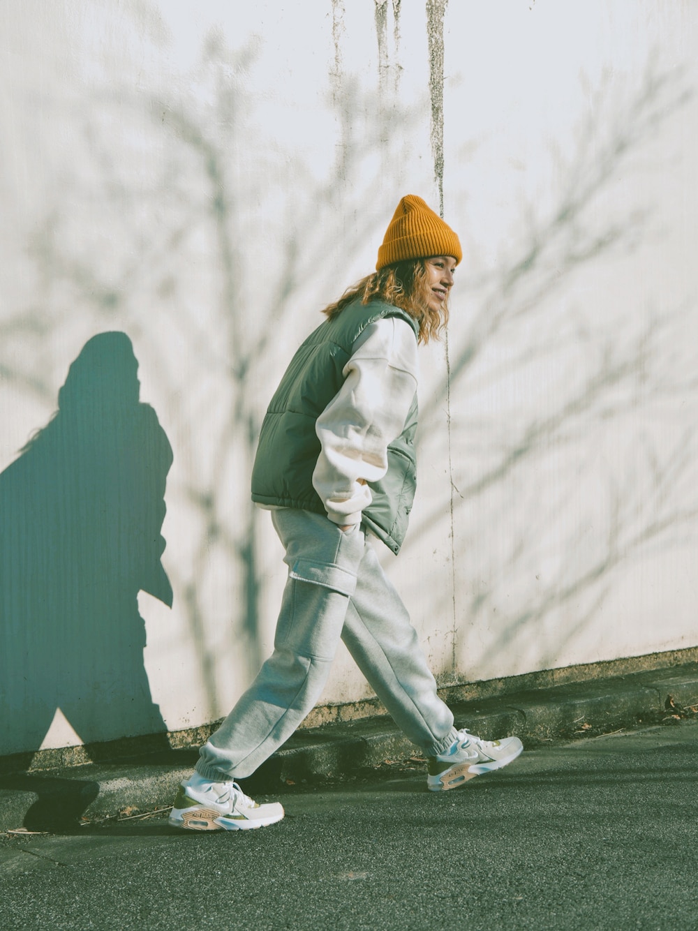 グリーン系のダウンベスト、ホワイト系のスウェット、グレー系のスウェットパンツを着用したレディースの冬コーディネートの1枚目の写真