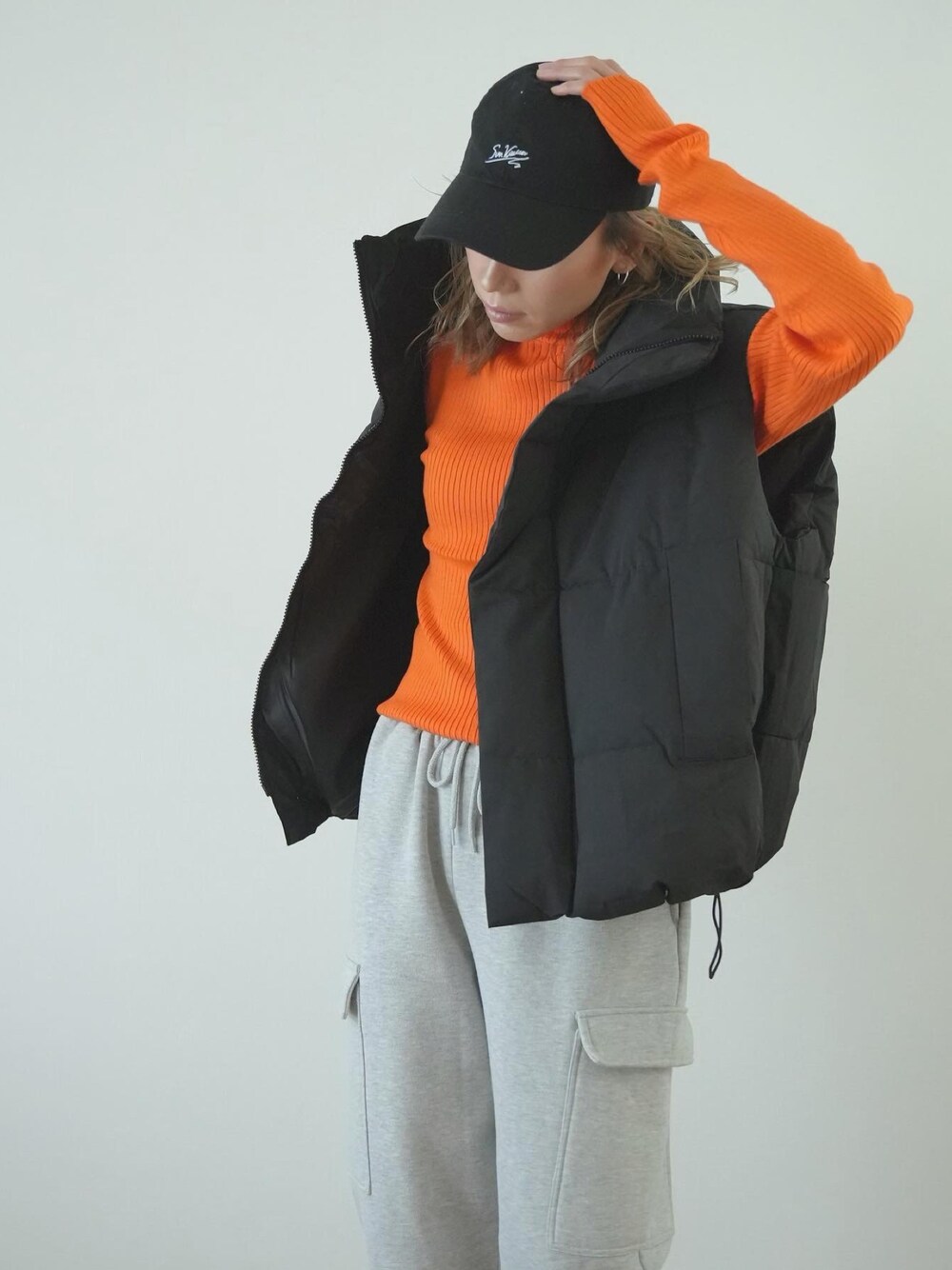 「冬コーデ、ストリート、カラーニット、オレンジ、ハイネック、ダウンベスト、スウェットパンツ、オトナ女子、大人コーデ、ブラック、ラフ、キャップ、パンツスタイル、リラックススタイル、ストリートコーデ」｜「Sun Vivianのアイテム（キャップ、ブラック系）」を使った、階上実穂さん（骨格ナチュラル・レディース・158cm）の冬コーディネートの1枚目の写真