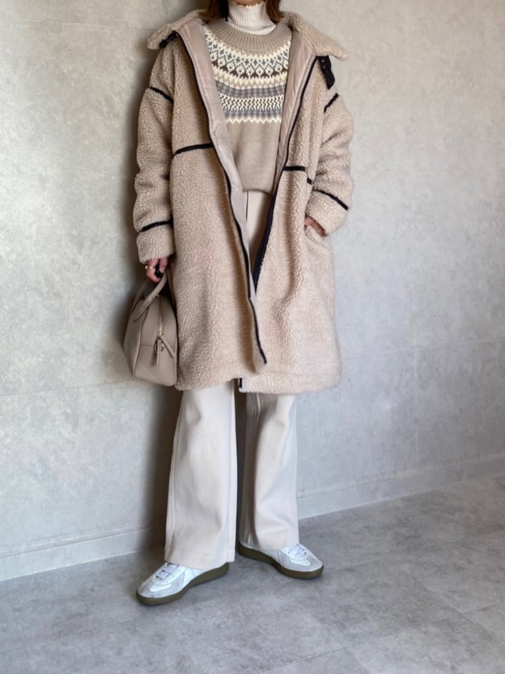 ベージュ系のムートンコート、ブラウン系のニット/セーター、ベージュ系のトートバッグを着用したレディースの冬コーディネートの1枚目の写真