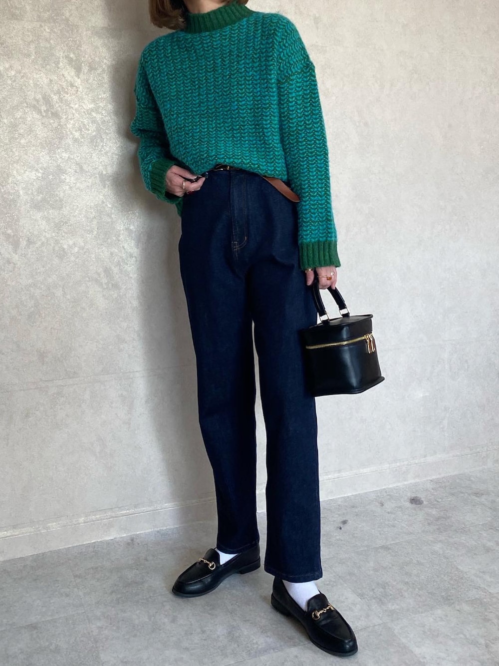 グリーン系のニット/セーター、ブルー系のデニムパンツ、ブラック系のショルダーバッグを着用したレディースの春コーディネートの1枚目の写真
