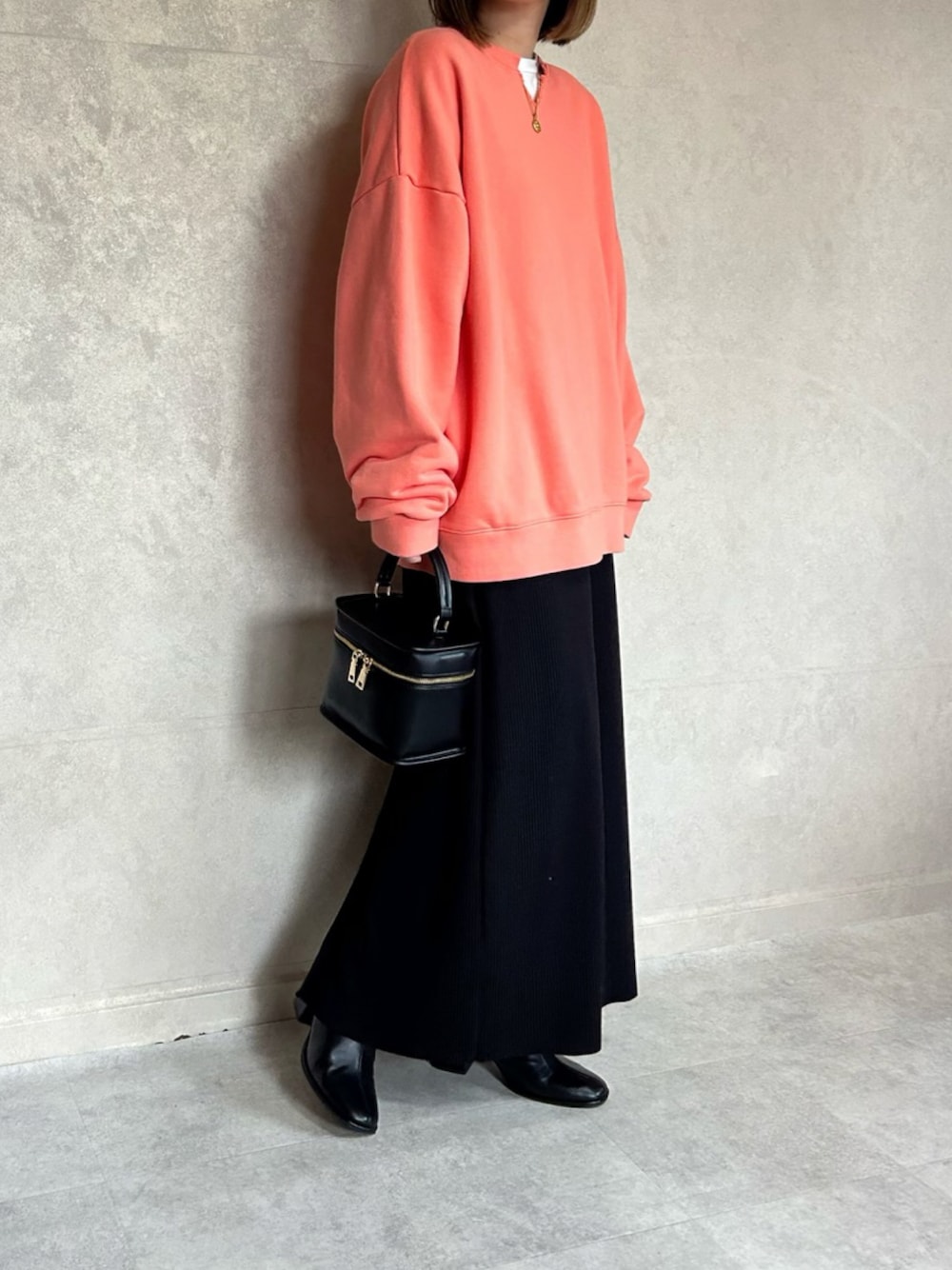 オレンジ系のスウェット、ブラック系のショルダーバッグを着用したレディースの春コーディネートの1枚目の写真