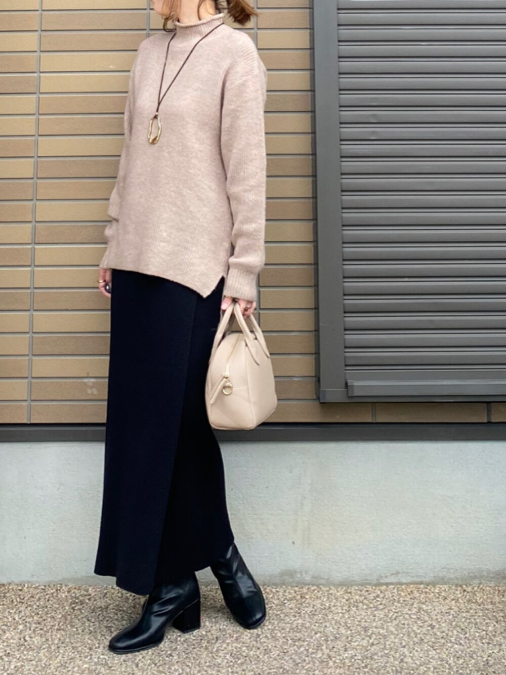 ベージュ系のニット/セーター、ベージュ系のトートバッグ、ブラック系のスカートを着用したレディースの秋コーディネートの1枚目の写真