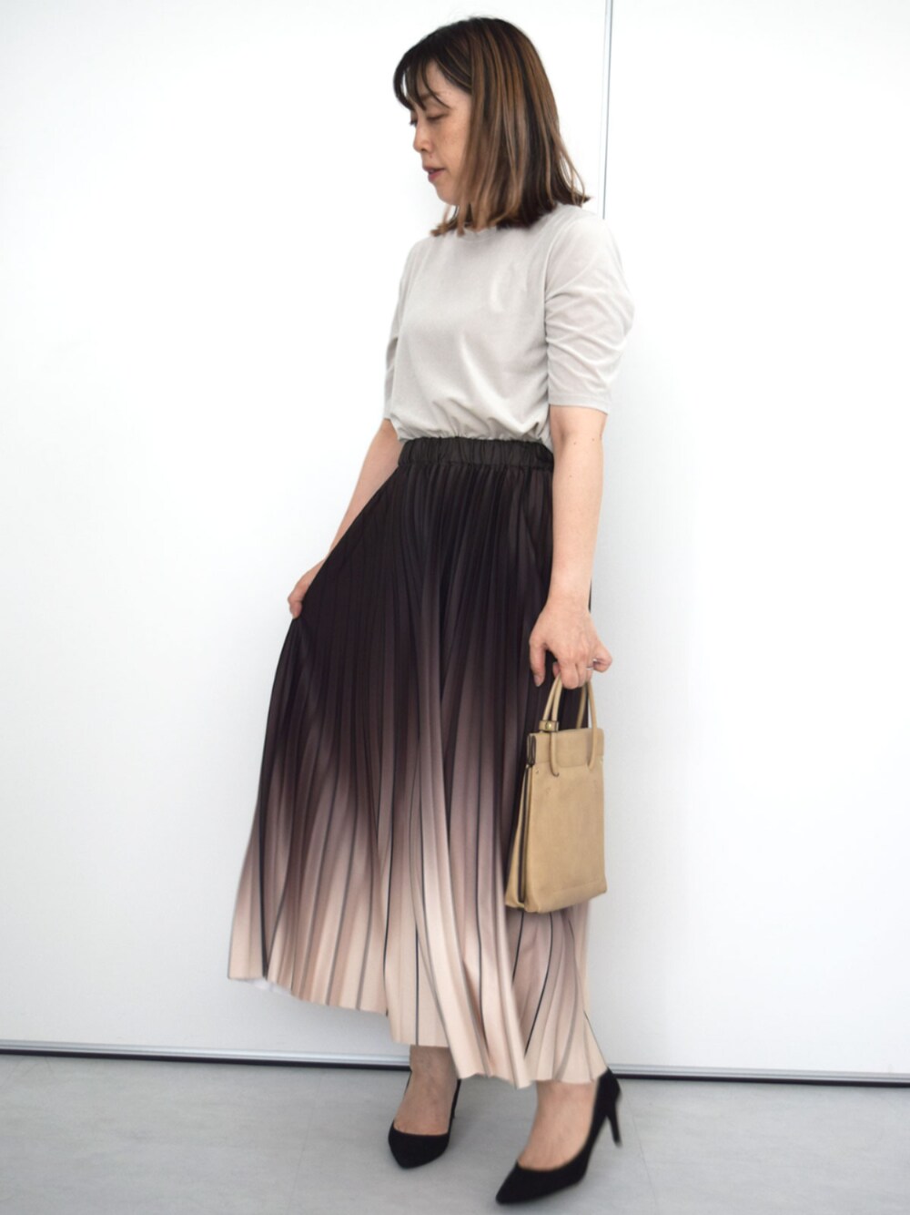 ブラウン系のスカート、ベージュ系のTシャツ/カットソーを着用したレディースの秋コーディネートの1枚目の写真