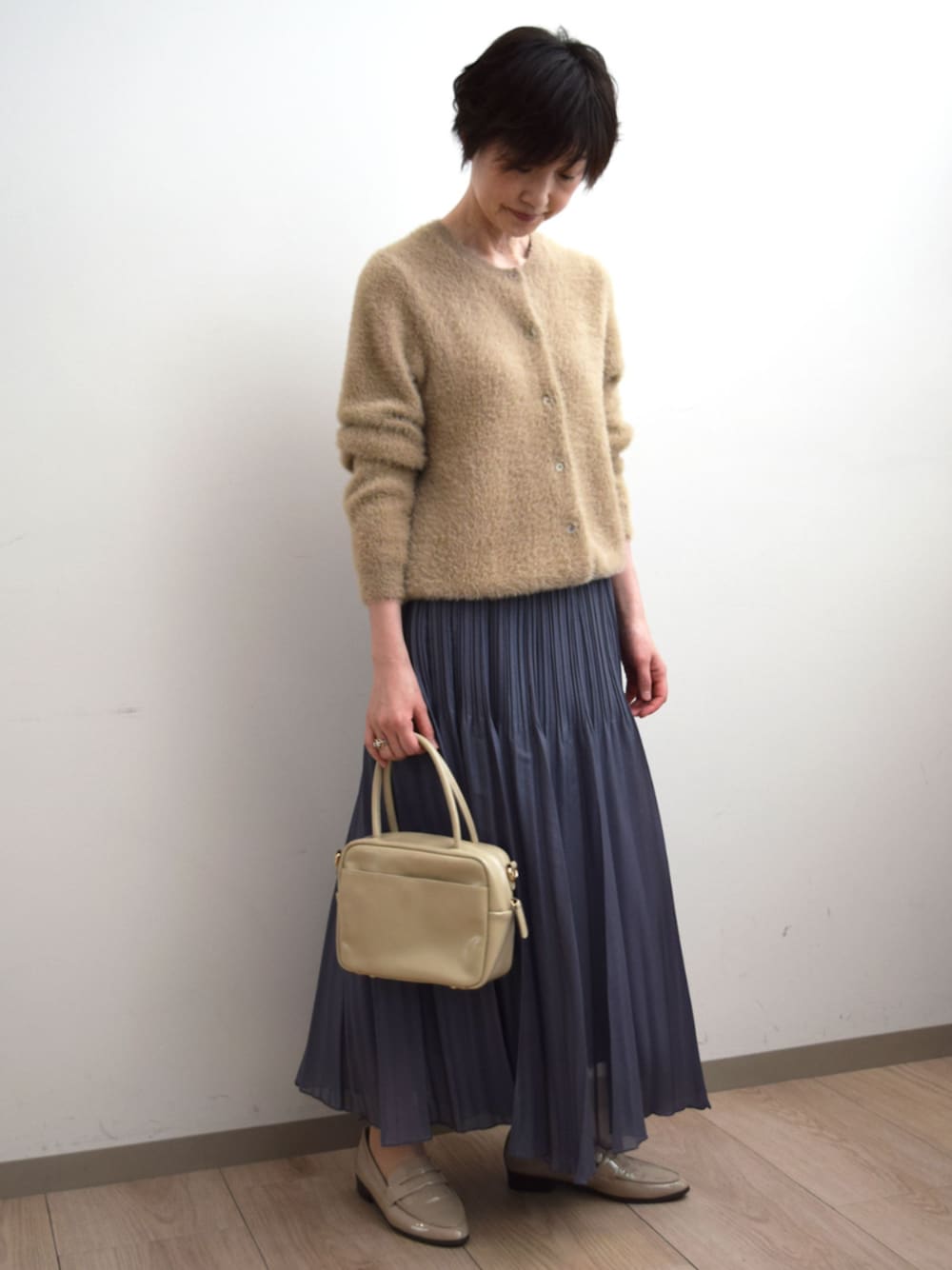 グレー系のスカート、ベージュ系のカーディガン/ボレロを着用したレディースの秋コーディネートの1枚目の写真