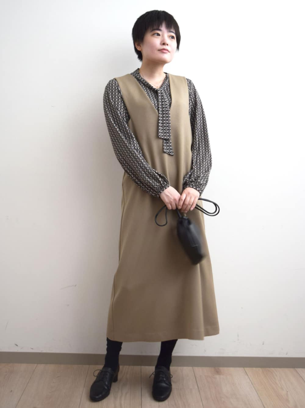 ベージュ系のジャンパースカート、ブラウン系のTシャツ/カットソーを着用したレディースの秋コーディネートの1枚目の写真