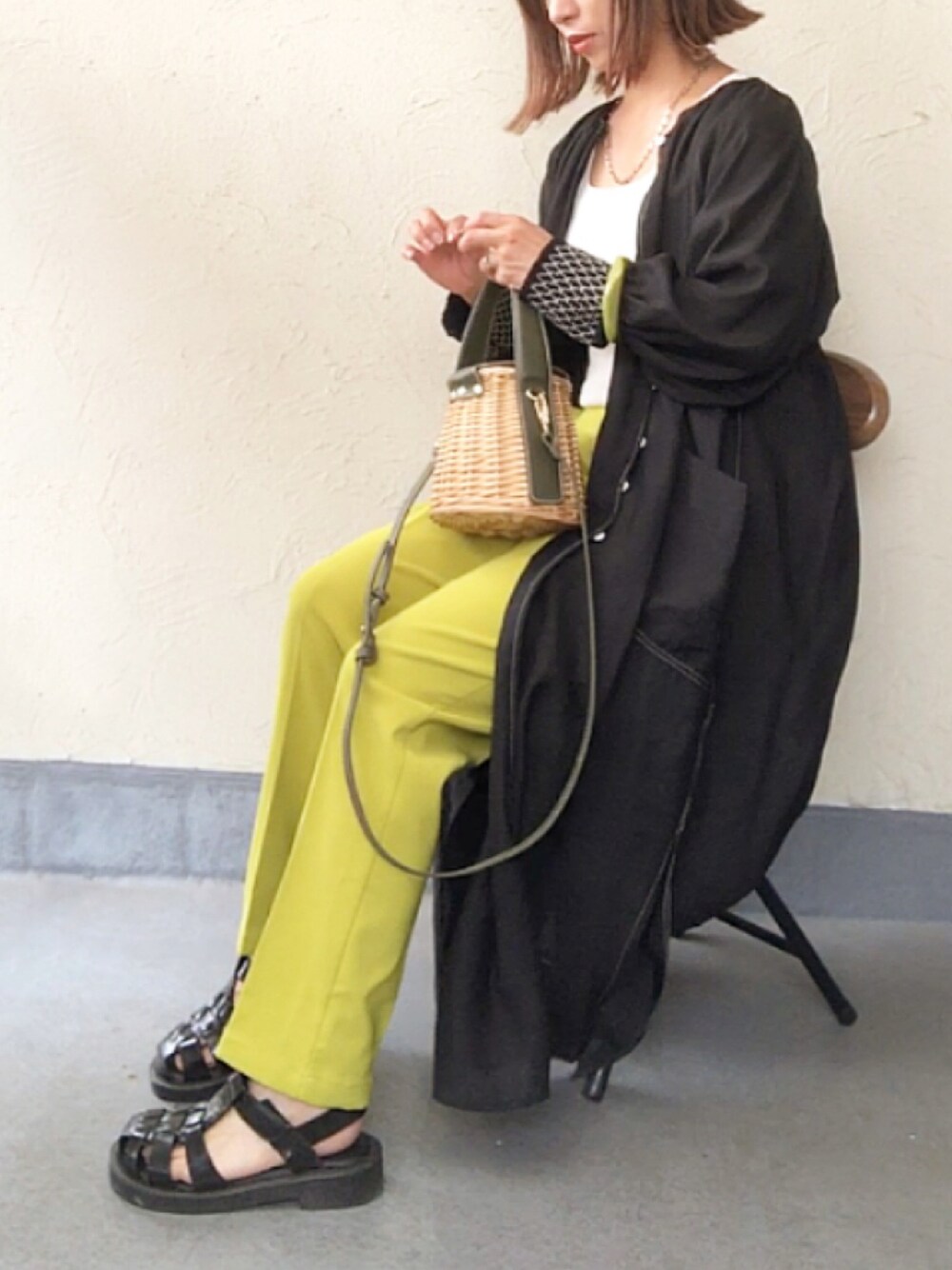 ブラック系のシャツ/ブラウス、ベージュ系のかごバッグ、グリーン系のスラックスを着用したレディースの春コーディネートの1枚目の写真