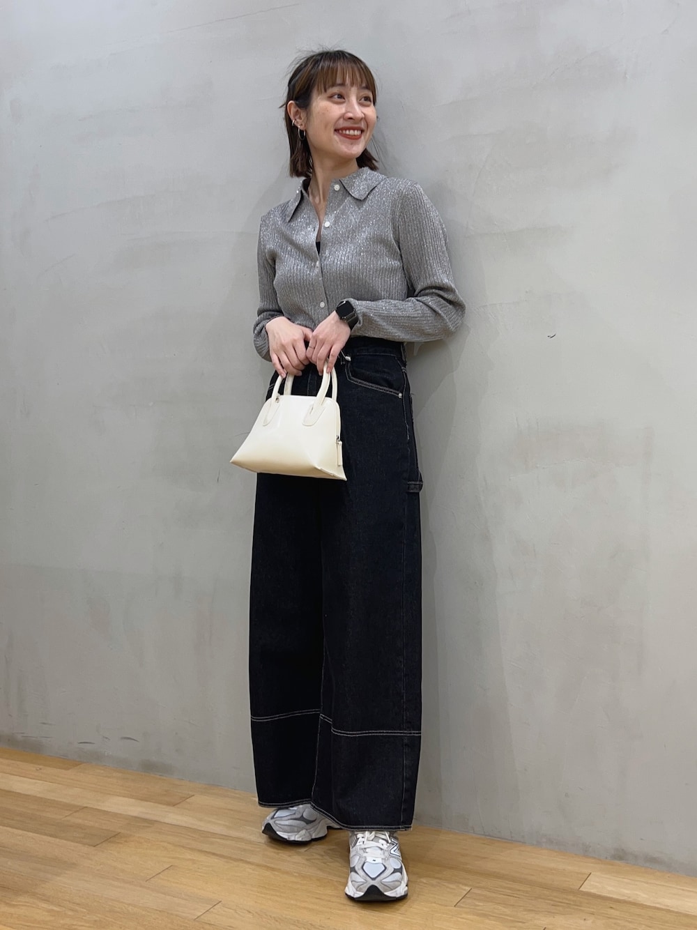 ブラック系のデニムパンツ、グレー系のニット/セーター、ホワイト系のショルダーバッグを着用したレディースの冬コーディネートの1枚目の写真