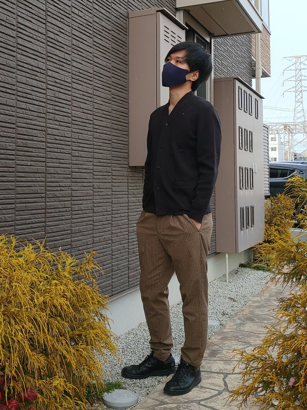 ベージュ系のスラックス、ブラック系のカーディガン/ボレロ、ブラック系のスニーカーを着用したメンズの冬コーディネートの2枚目の写真