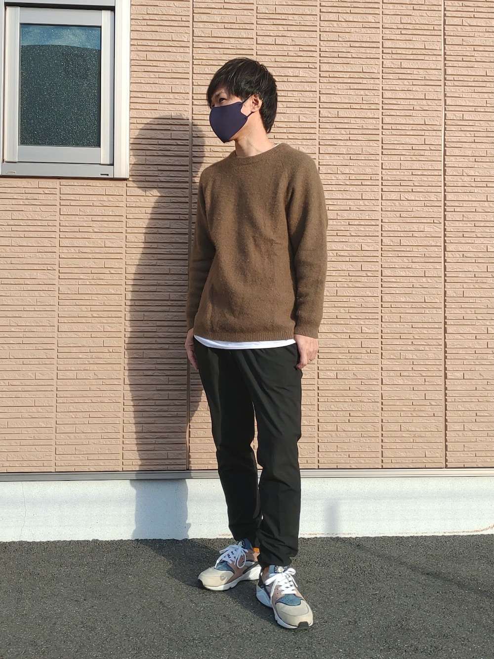 ブルー系のスラックス、グリーン系のニット/セーター、ベージュ系のスニーカーを着用したメンズの春コーディネートの2枚目の写真