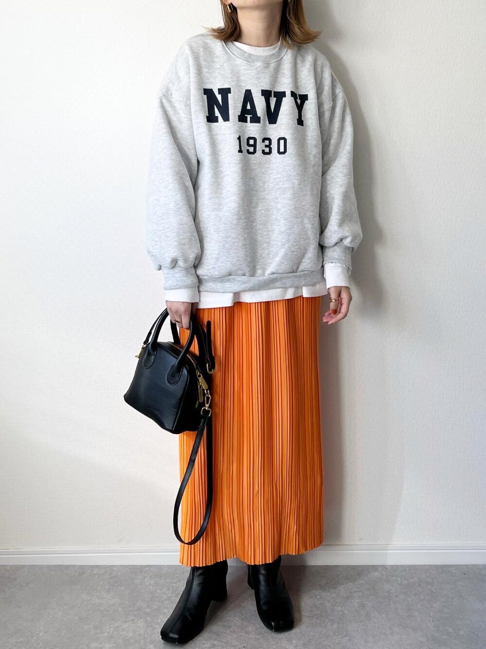 グレー系のスウェット、ブラック系のバッグ、オレンジ系のスカートを着用したレディースの秋コーディネートの1枚目の写真