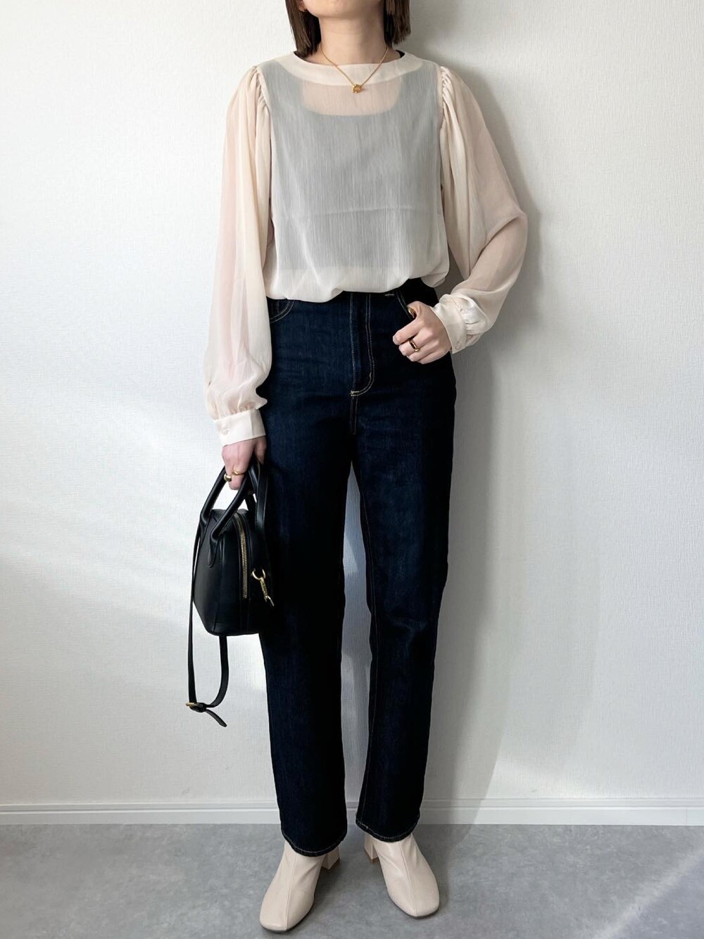 ベージュ系のシャツ/ブラウス、ブルー系のデニムパンツ、ブラック系のバッグを着用したレディースの冬コーディネートの1枚目の写真