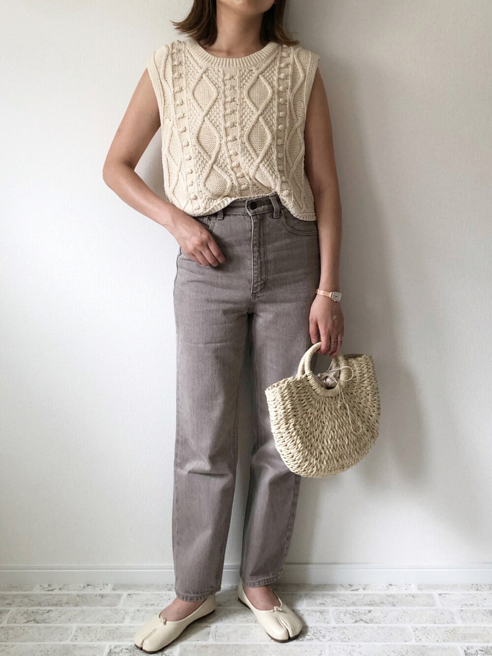 ブラウン系のデニムパンツ、ホワイト系のニット/セーター、ベージュ系のかごバッグを着用したレディースの夏コーディネートの1枚目の写真
