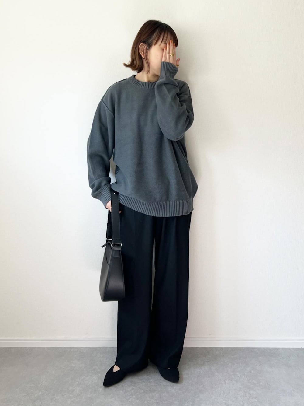 グレー系のニット/セーター、ブラック系のパンツ、ブラック系のバッグを着用したレディースの春コーディネートの1枚目の写真