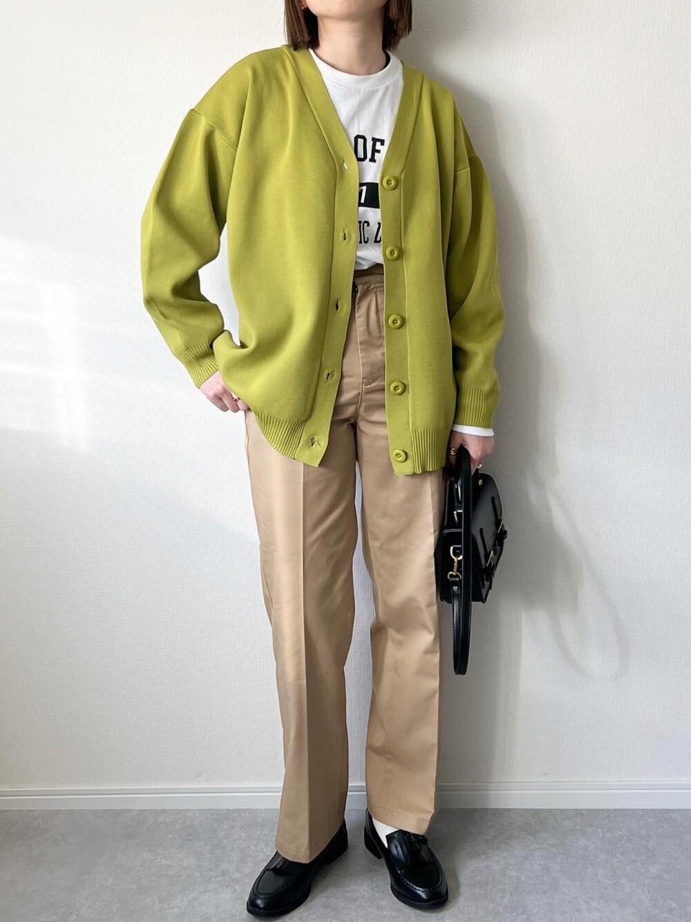 グリーン系のカーディガン/ボレロ、ホワイト系のTシャツ/カットソー、ベージュ系のチノパンツを着用したレディースの冬コーディネートの1枚目の写真