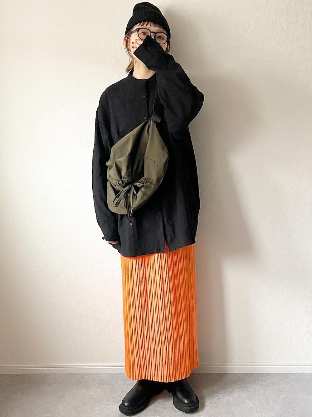 ブラック系のシャツ/ブラウス、グリーン系のショルダーバッグ、オレンジ系のスカートを着用したレディースの冬コーディネートの1枚目の写真