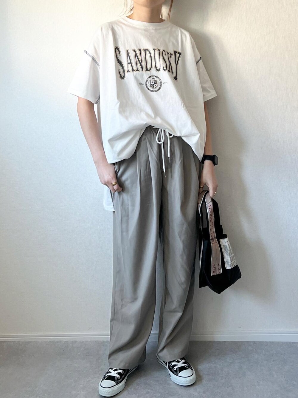 ベージュ系のパンツ、ブラック系のショルダーバッグ、ブラック系のスニーカーを着用したレディースの春コーディネートの1枚目の写真