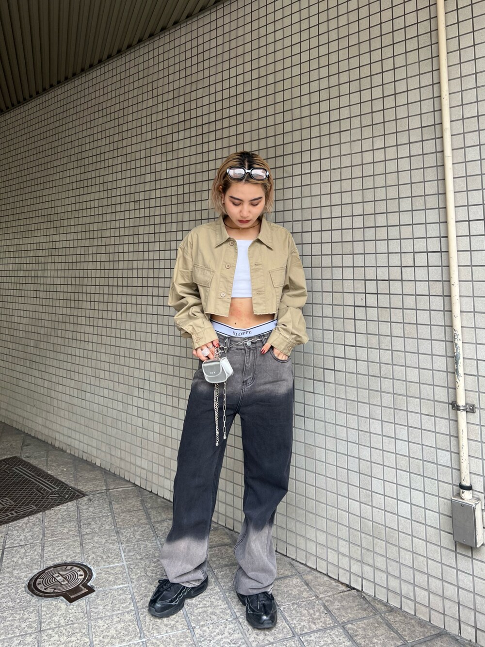 ブラック系のデニムパンツ、ベージュ系のミリタリージャケット、シルバー系のショルダーバッグを着用したレディースの春コーディネートの1枚目の写真