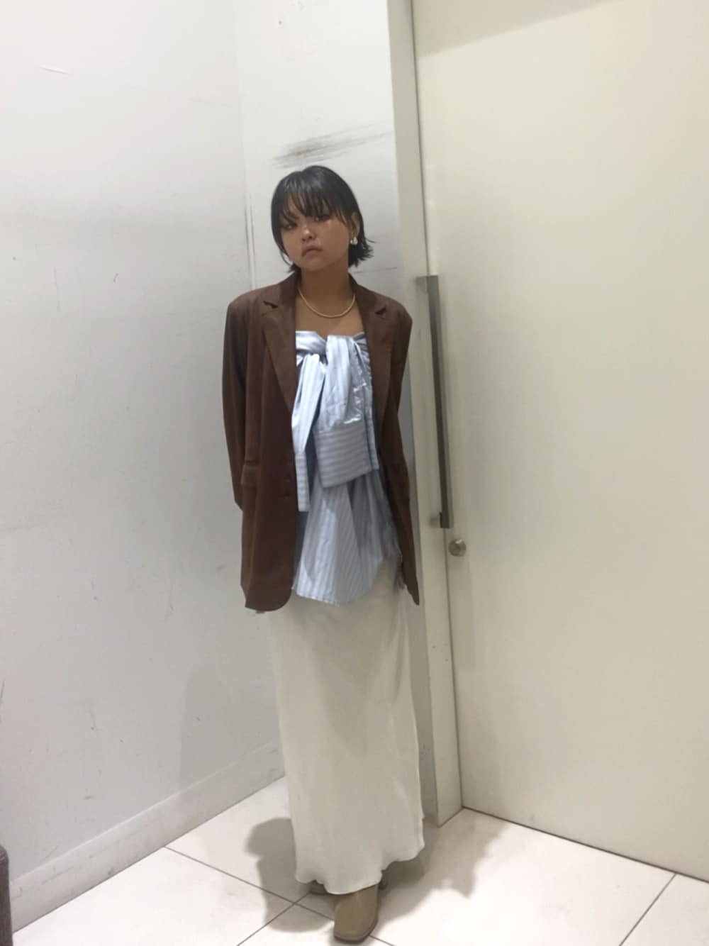 ブルー系のシャツ/ブラウス、ブラウン系のその他アウター、ホワイト系のスカートを着用したレディースの秋コーディネートの1枚目の写真