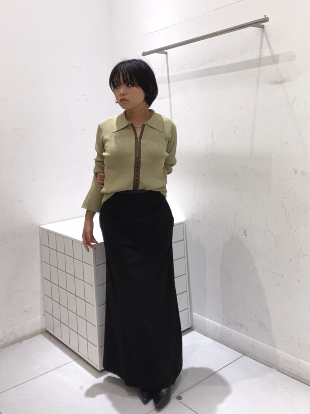 ブラック系のスカート、イエロー系のカーディガン/ボレロ、ブラック系のブーツを着用したレディースの秋コーディネートの1枚目の写真