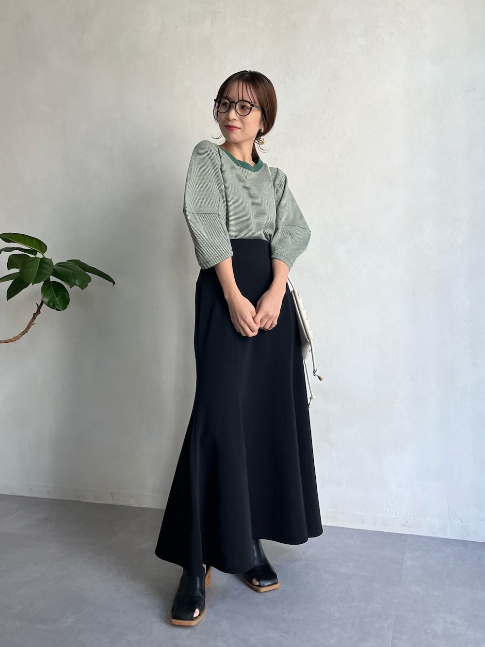 グリーン系のTシャツ/カットソー、ブラック系のスカート、ホワイト系のショルダーバッグを着用したレディースの春コーディネートの2枚目の写真