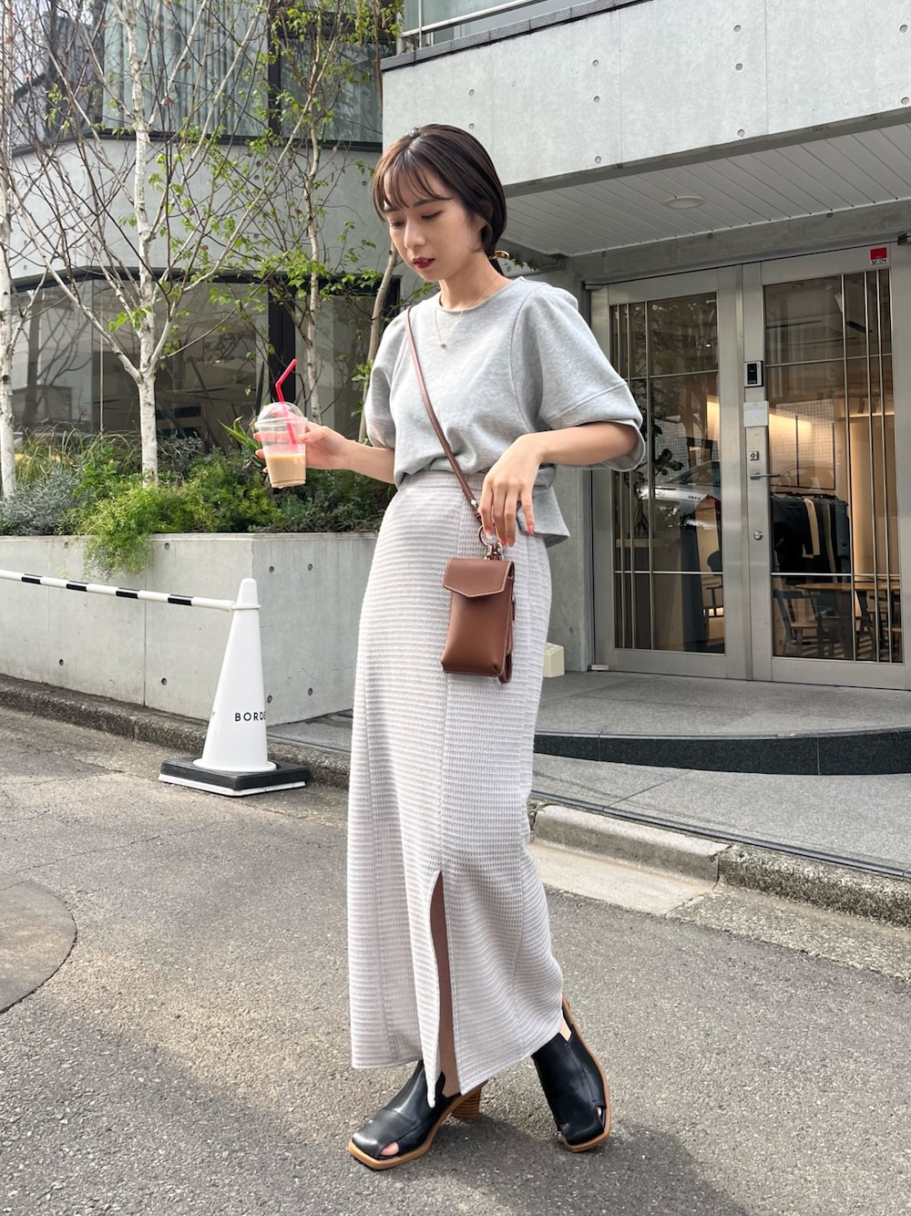 グレー系のTシャツ/カットソー、グレー系のスカート、ブラウン系のショルダーバッグを着用したレディースの春コーディネートの2枚目の写真