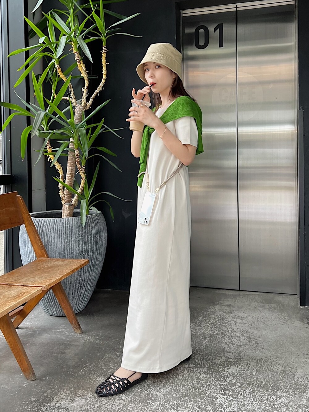 ホワイト系のワンピース、グリーン系のカーディガン/ボレロ、ブラック系のパンプスを着用したレディースの春コーディネートの2枚目の写真