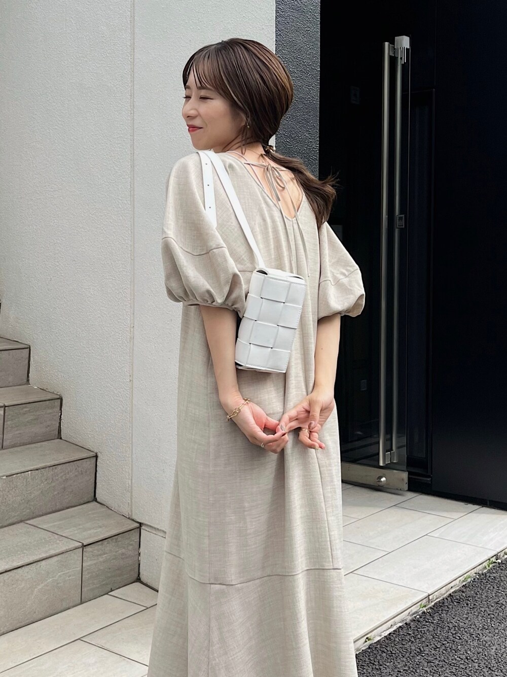 ベージュ系のワンピース、ホワイト系のトートバッグ、ブラック系のサンダルを着用したレディースの夏コーディネートの2枚目の写真