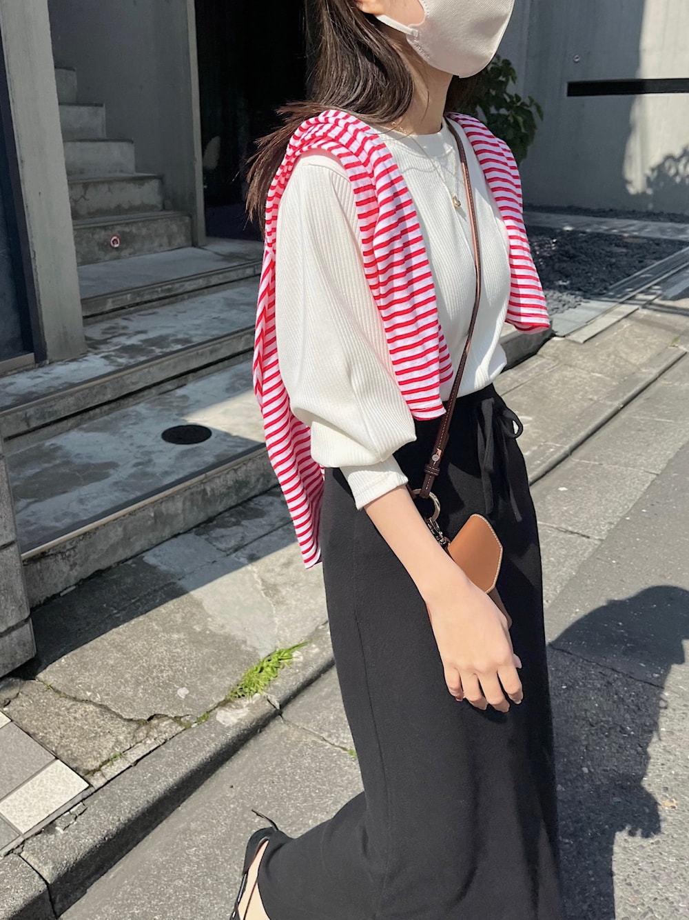 ブラック系のスカート、ブラウン系のショルダーバッグ、ブラック系のパンプスを着用したレディースの春コーディネートの4枚目の写真