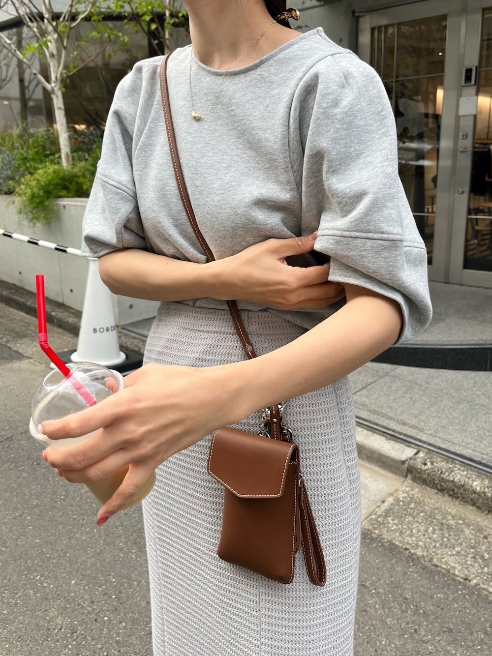 グレー系のTシャツ/カットソー、グレー系のスカート、ブラウン系のショルダーバッグを着用したレディースの春コーディネートの5枚目の写真