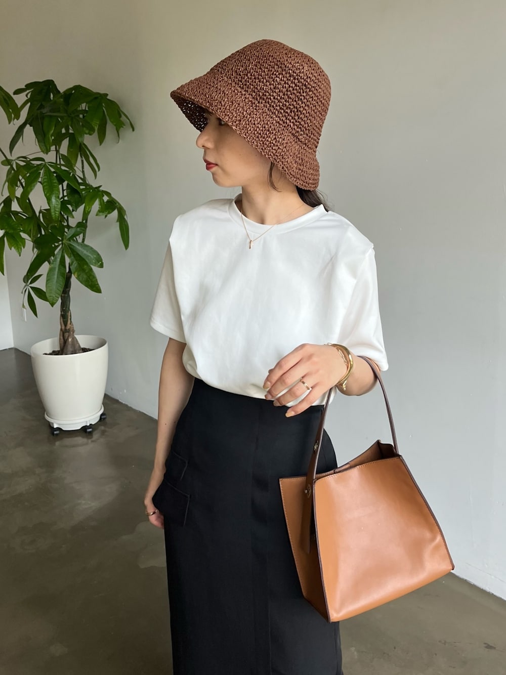 ホワイト系のTシャツ/カットソー、ブラック系のスカート、ブラウン系のハットを着用したレディースの春コーディネートの4枚目の写真