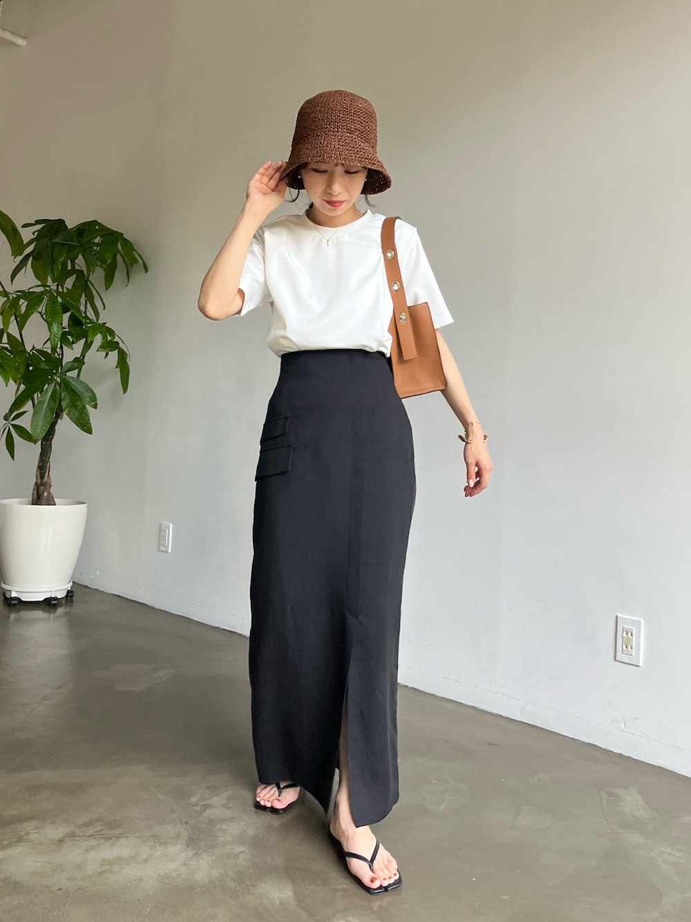 ホワイト系のTシャツ/カットソー、ブラック系のスカート、ブラウン系のハットを着用したレディースの春コーディネートの2枚目の写真