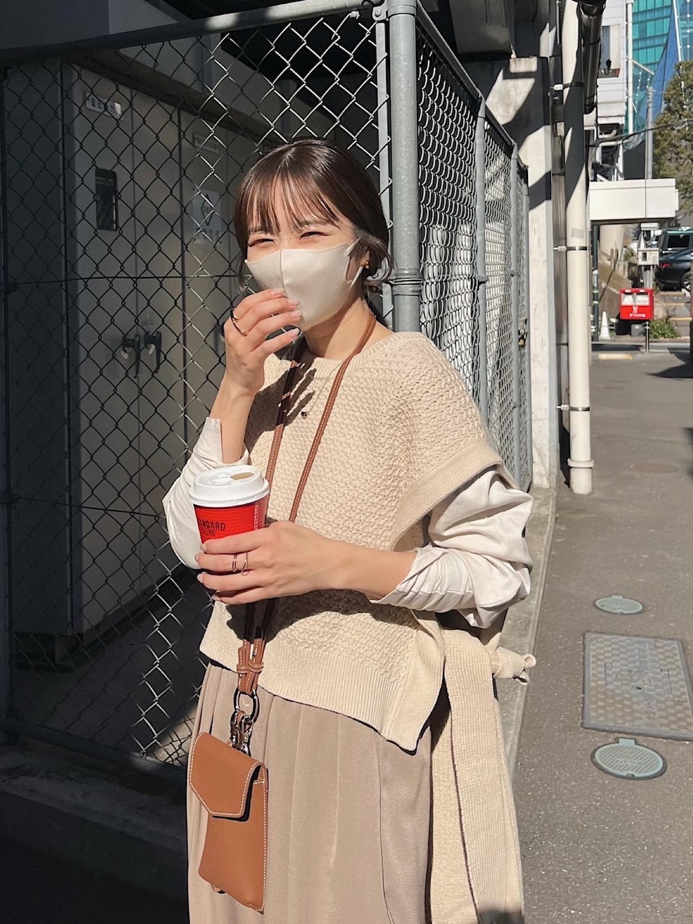 ベージュ系のベスト、ベージュ系のモッズコート、ブラウン系のショルダーバッグを着用したレディースの春コーディネートの2枚目の写真