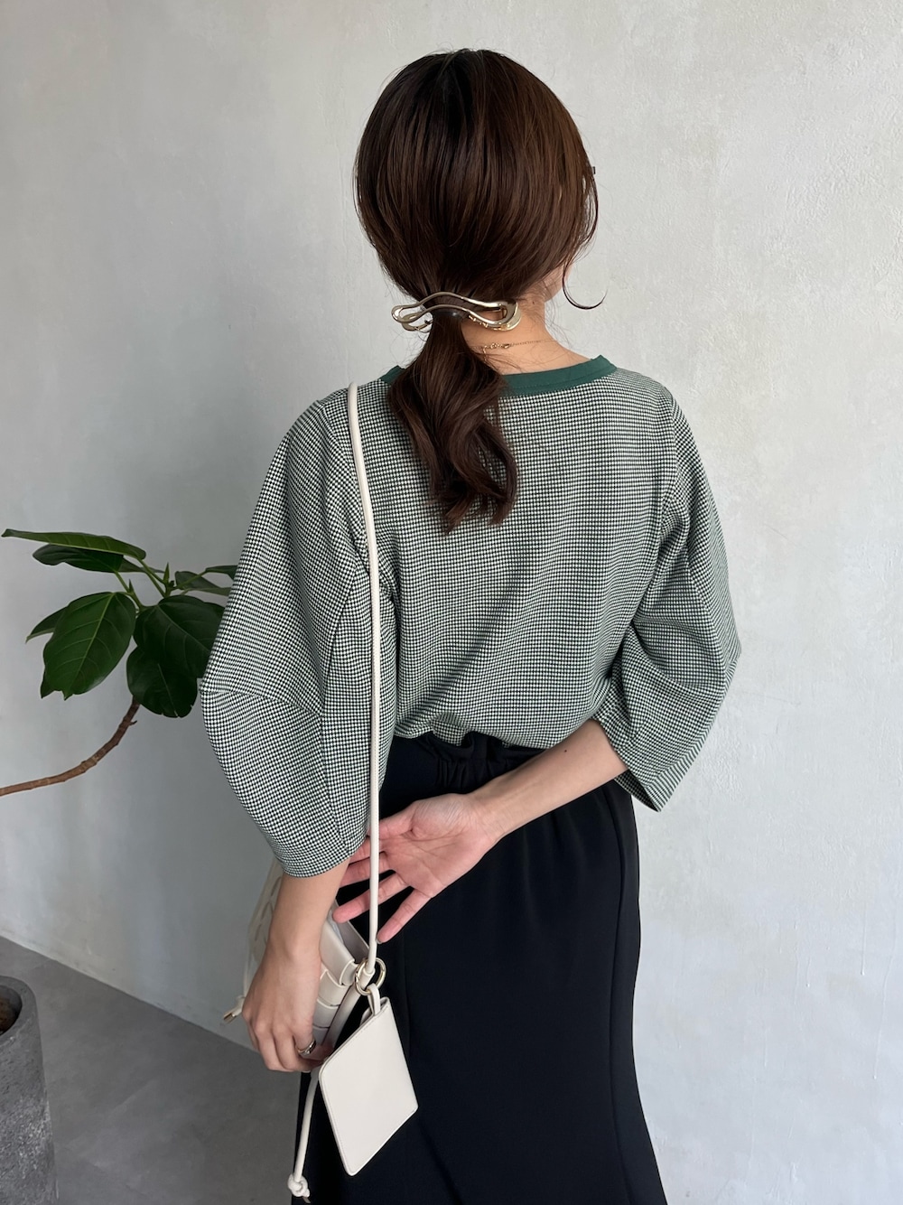 グリーン系のTシャツ/カットソー、ブラック系のスカート、ホワイト系のショルダーバッグを着用したレディースの春コーディネートの5枚目の写真